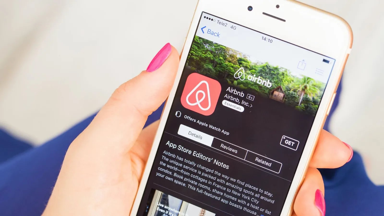 A hand holding a phone showing the Airbnb app.