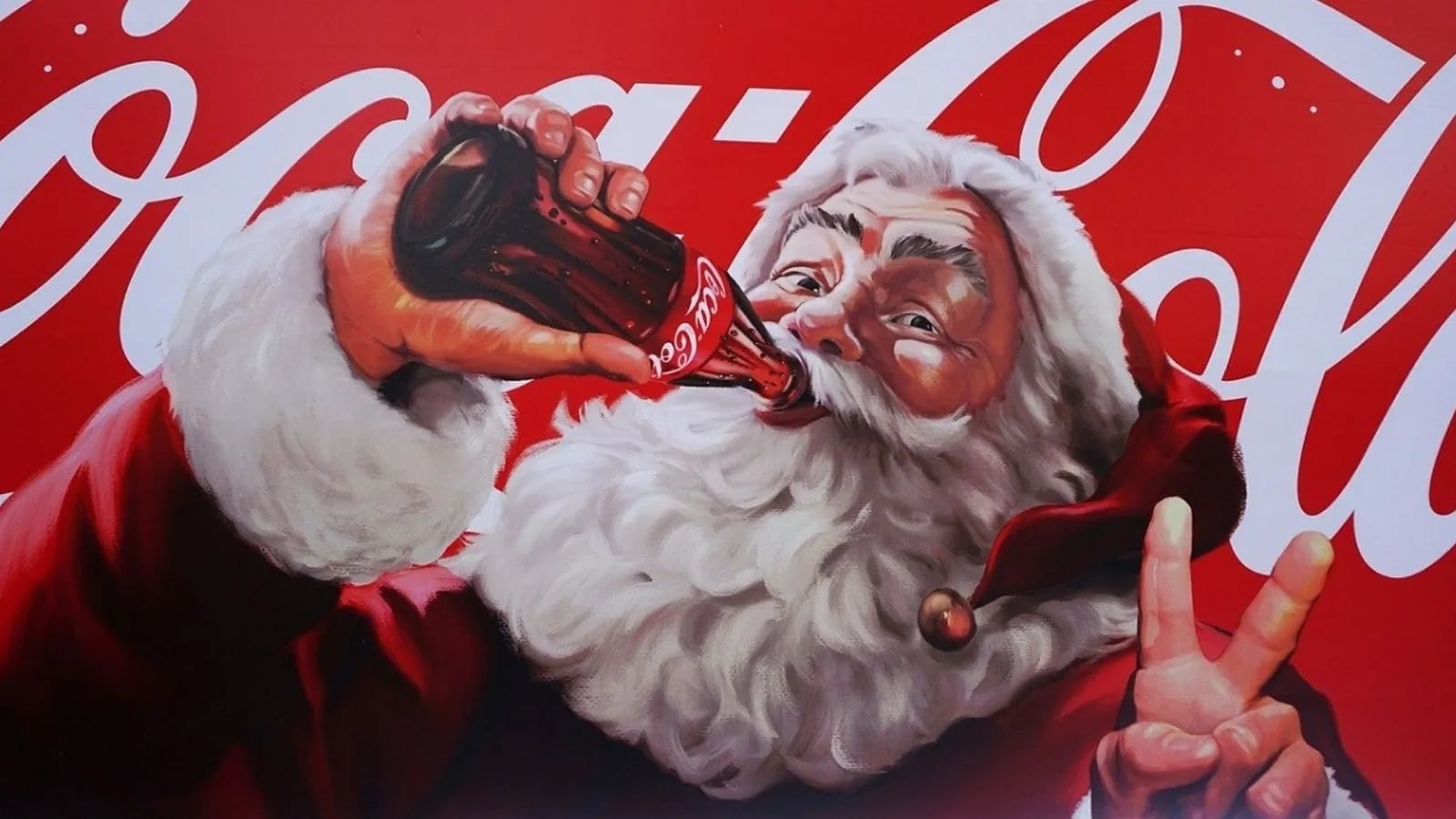 A vintage Coca-Cola Christmas ad showing Santa holding a bottle of Coke.