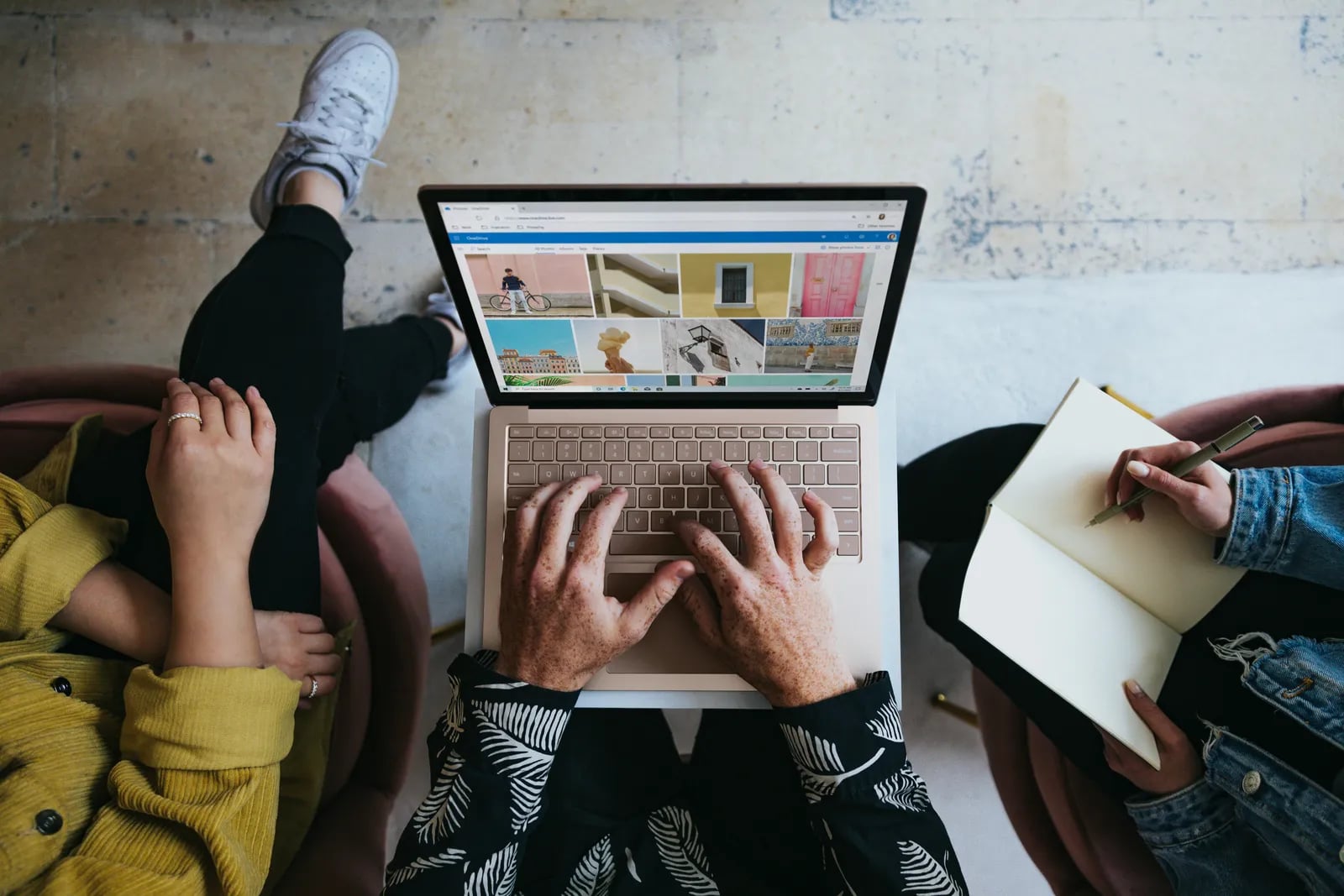A person working on a laptop beside a notebook.